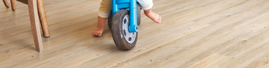 toddler riding a toy motocrycle on a cork floor
